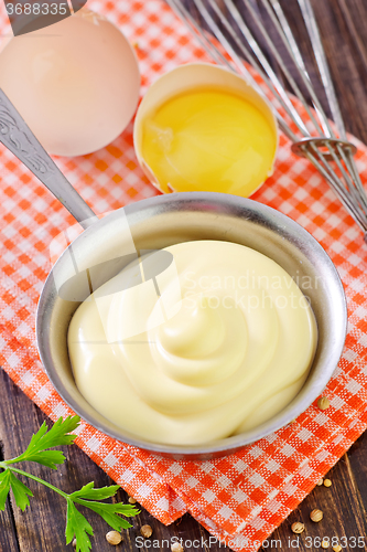 Image of mayonnaise in metal spoon on wooden board