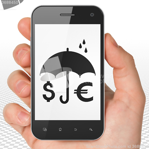 Image of Security concept: Hand Holding Smartphone with Money And Umbrella on display