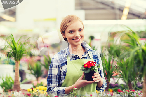 Image of happy woman holding flowers in greenhouse