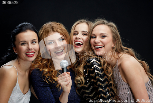 Image of happy young women with microphone singing karaoke