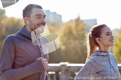 Image of happy couple with earphones running in city