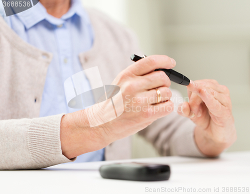 Image of senior woman with glucometer checking blood sugar