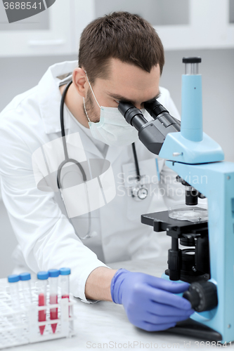 Image of young scientist looking to microscope in lab