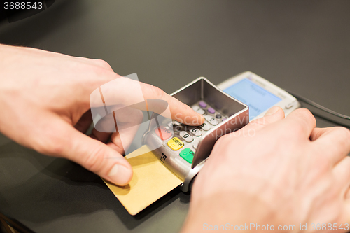 Image of hand entering pin code to bank terminal