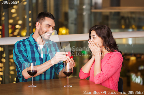 Image of man giving engagement ring to woman at restaurant