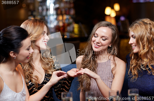 Image of woman showing engagement ring to her friends