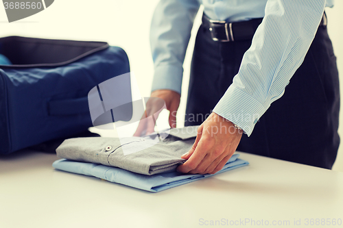 Image of businessman packing clothes into travel bag