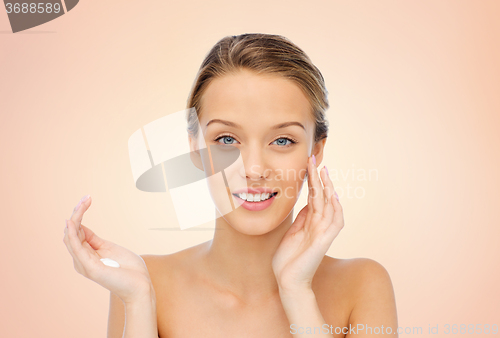 Image of happy young woman applying cream to her face