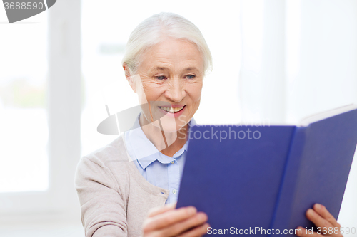 Image of happy smiling senior woman reading book at home