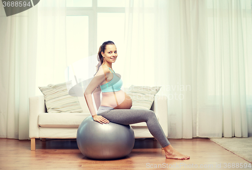 Image of happy pregnant woman exercising on fitball at home