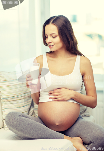 Image of happy pregnant woman drinking milk at home