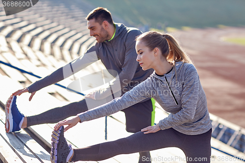 Image of couple stretching leg on stands of stadium