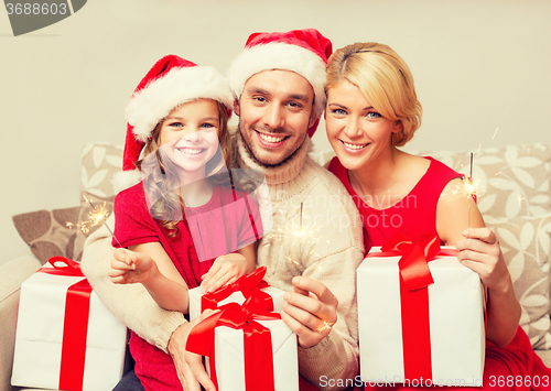 Image of smiling family holding gift boxes and sparkles