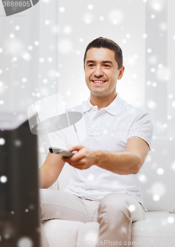 Image of smiling man with remote control watching tv