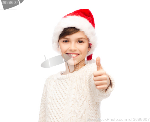 Image of smiling happy boy in santa hat showing thumbs up