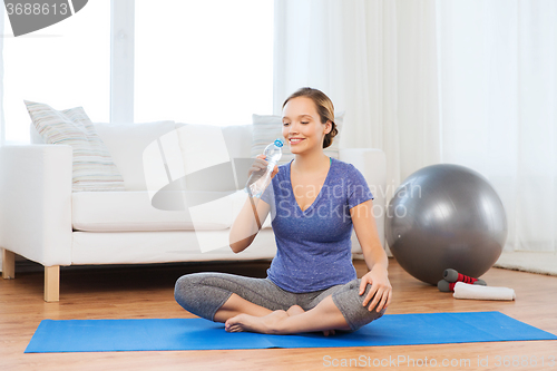 Image of happy woman with water bottle exercising at home