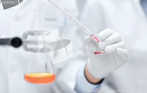 Image of close up of scientists filling test tube in lab