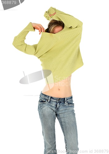 Image of Woman in jeans takes off a green sweater