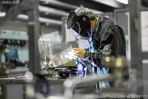 Image of Industrial worker welding in metal factory.