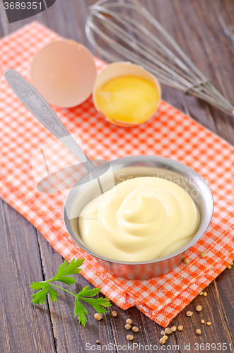 Image of mayonnaise in metal spoon on wooden board