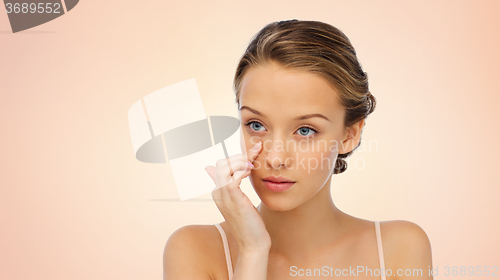 Image of young woman applying cream to her face
