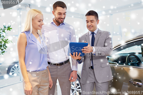 Image of happy couple with car dealer in auto show or salon