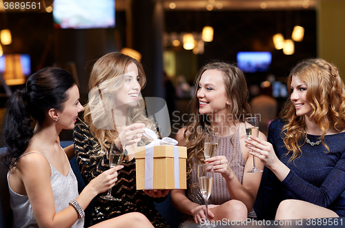 Image of happy women with champagne and gift at night club