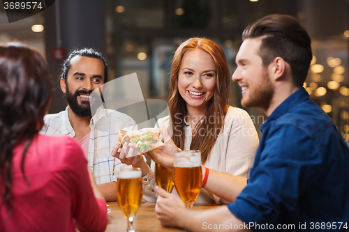 Image of friends eating pizza with beer at restaurant