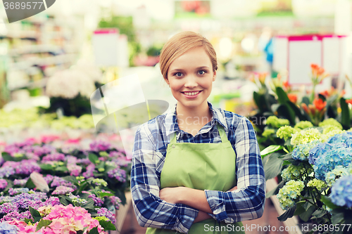 Image of happy woman with flowers in greenhouse