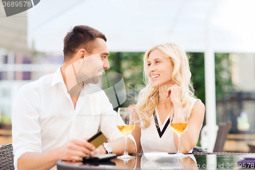 Image of happy couple with bank card and bill at restaurant