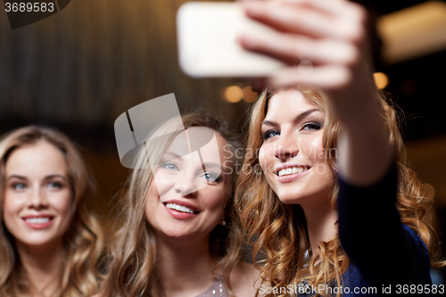 Image of women with smartphone taking selfie at night club