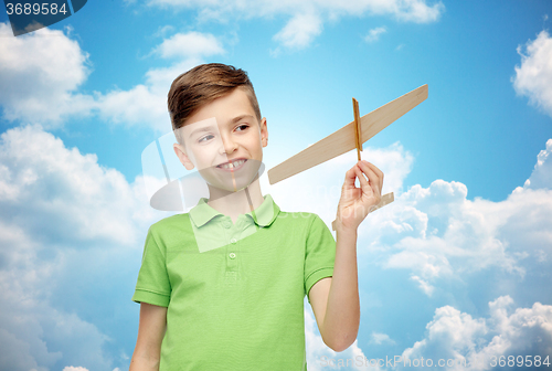 Image of happy boy in green polo t-shirt with toy airplane