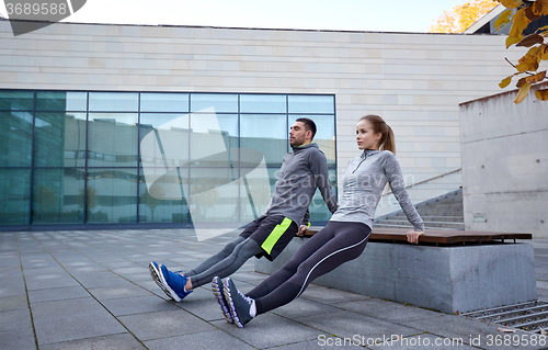 Image of couple doing triceps dip exercise outdoors