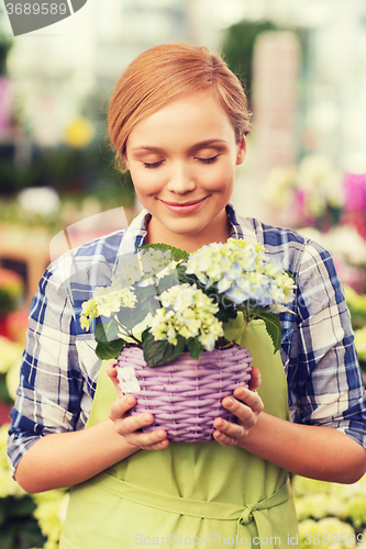 Image of happy woman smelling flowers in greenhouse