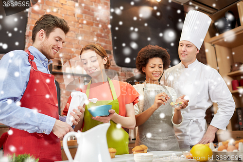 Image of happy friends and chef cook baking in kitchen