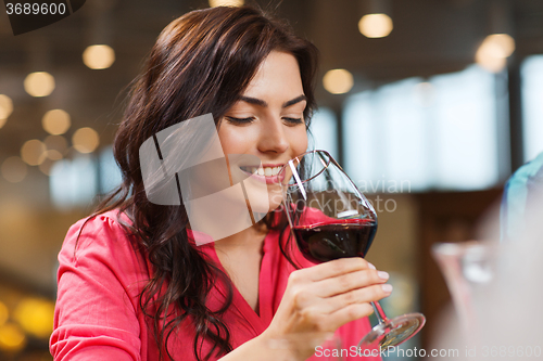 Image of smiling woman drinking red wine at restaurant