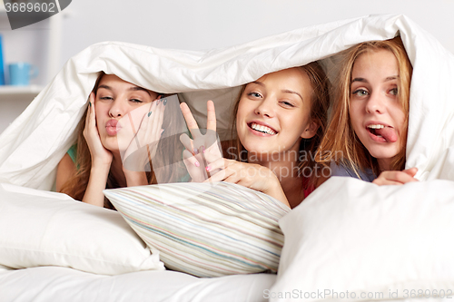 Image of happy young women in bed at home pajama party