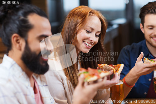 Image of friends eating pizza with beer at restaurant