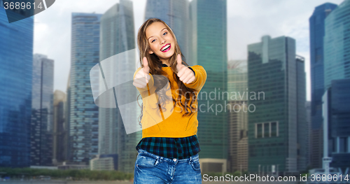 Image of happy young woman or teen girl showing thumbs up