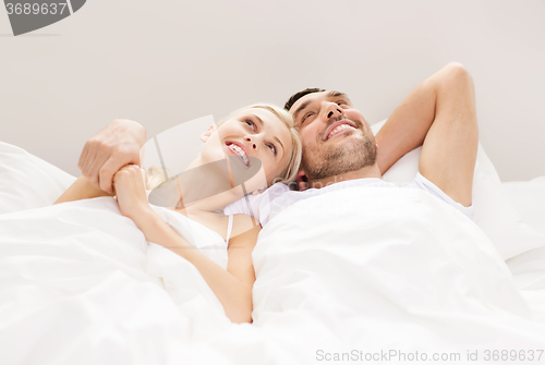 Image of happy couple lying in bed at home