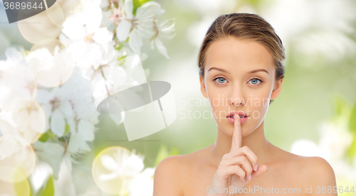 Image of beautiful young woman holding finger on lips