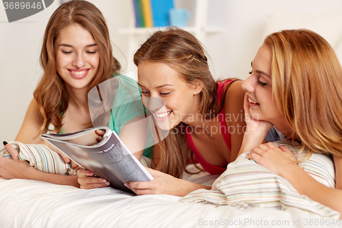 Image of friends or teen girls reading magazine at home