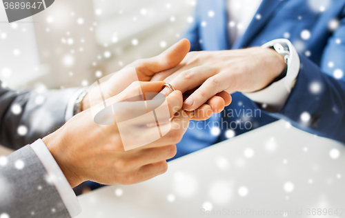 Image of close up of male gay couple hands and wedding ring