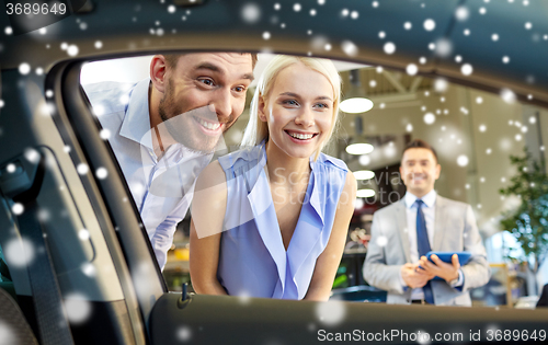 Image of happy couple looking inside car in auto show