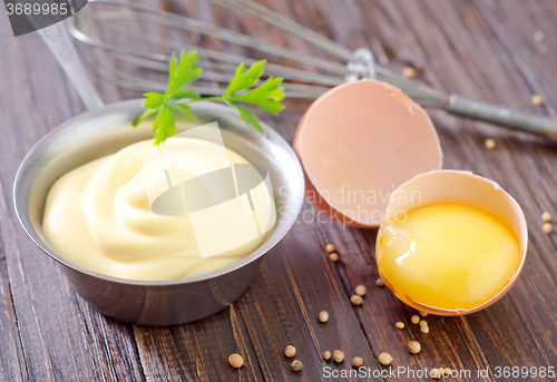 Image of mayonnaise in metal spoon on wooden board