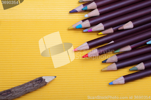 Image of Colored pencils on yellow cardboard background