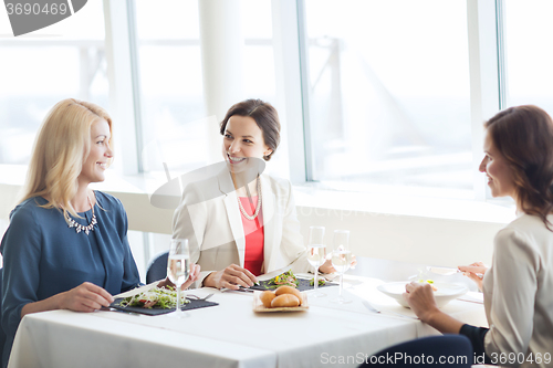 Image of happy women eating and talking at restaurant