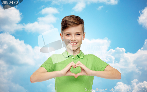 Image of happy boy showing heart hand sign over blue sky