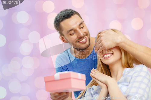 Image of smiling man surprises his girlfriend with present