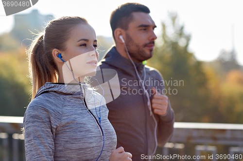 Image of happy couple with earphones running in city